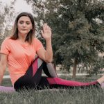 Adult woman practicing yoga on a mat in a park setting, displaying focused concentration.